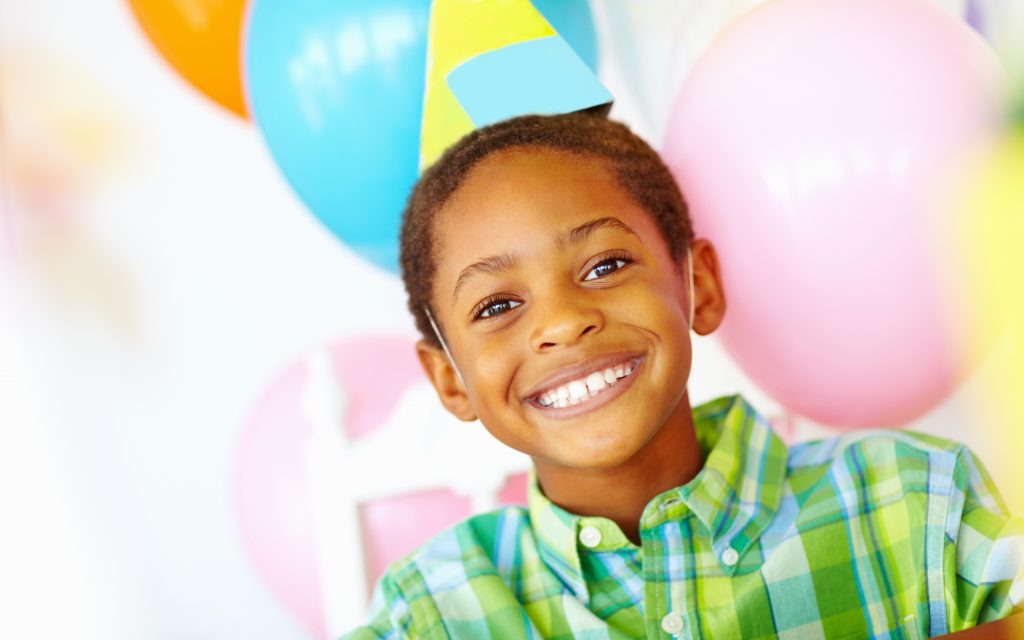 Closeup portrait of an African American birthday boy with balloons in the background