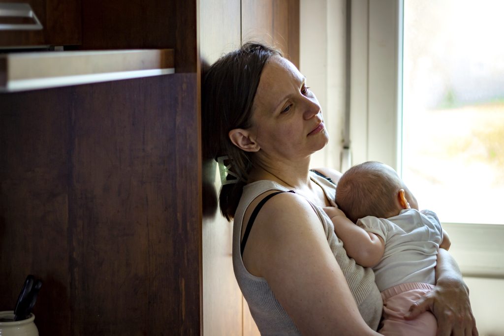 Tired concerned mother rocking sleeping baby. Postpartum Depression - SavvyMom