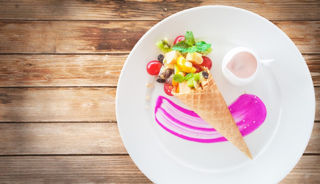 Fruit salad in an ice cream cone on wood background