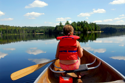 Young girl in canoe paddling on a scenic lake