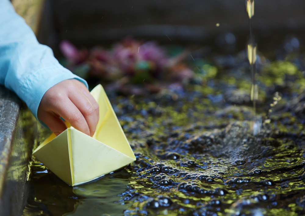 Boy Playing with Paper Boat in Water