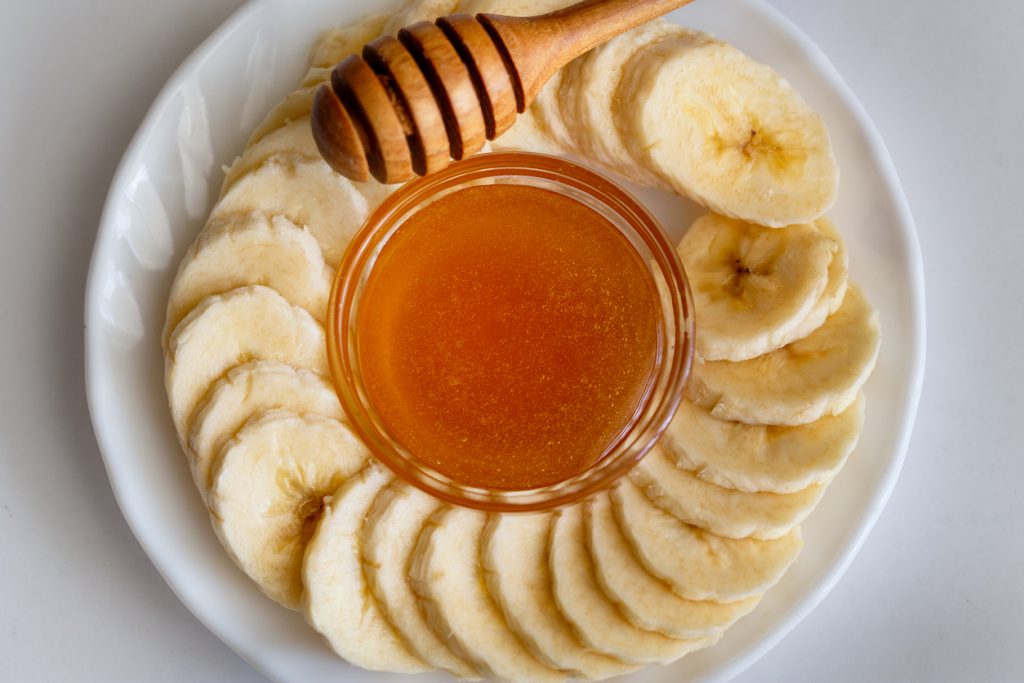 Sliced banana with honey separately on a plate