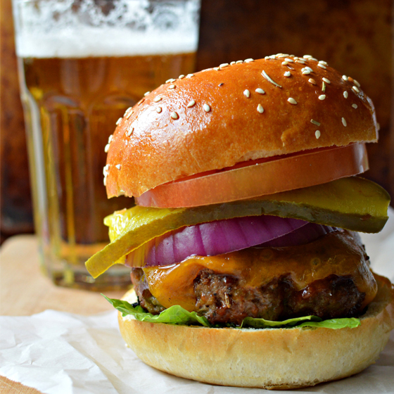 These big and beefy burgers are infused with a touch of beer, then brushed with a beer-based barbecue sauce while cooking. Be sure to butter and toast the buns before topping with the grilled patties—it will provide a barrier and keep the bread from turning soggy. 