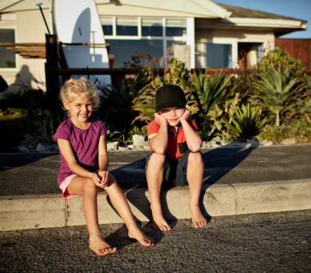 2 surf kids hanging out in front of their house