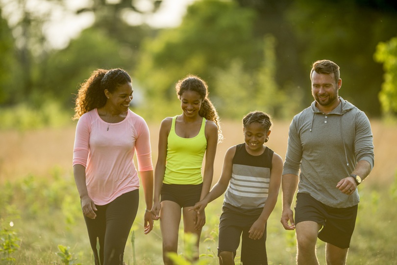 Family Walking Through a Field Tips for Raising Active Adults - SavvyMom
