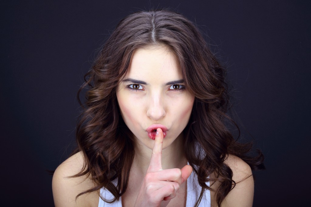 Young woman asking to keep silent