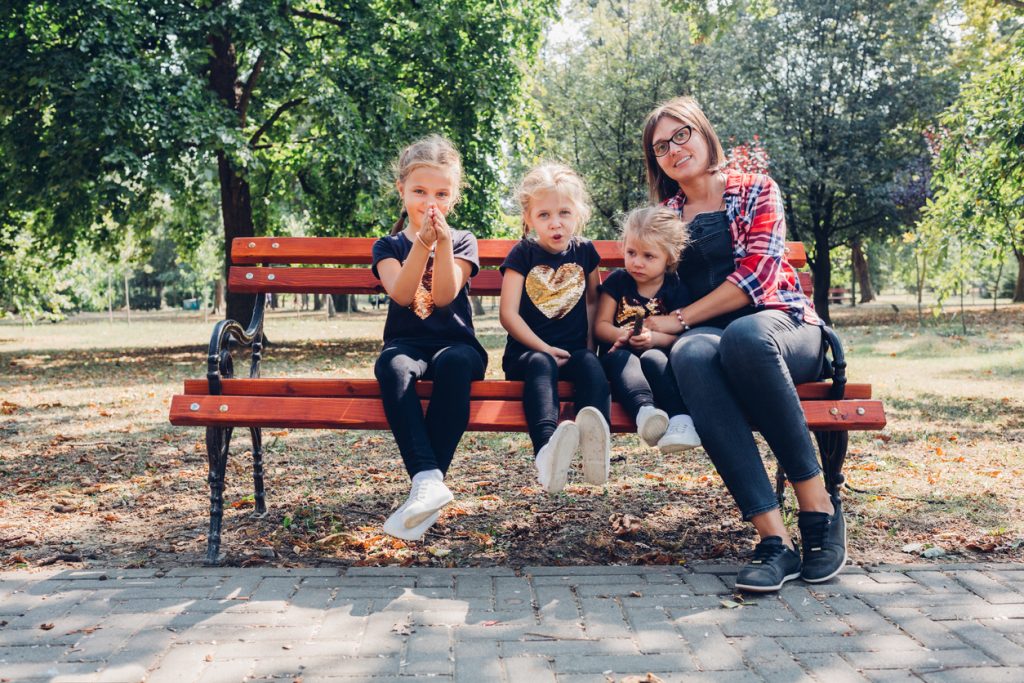 Pregnant mother with daughters in park.