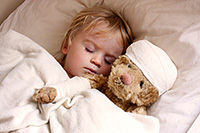 Childinbedwithbandagewrappedteddybear