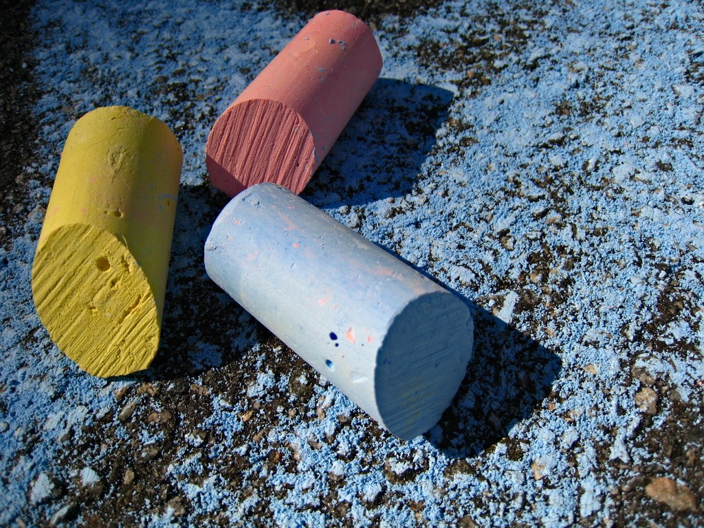 Pieces of used sidewalk chalk on street.