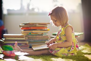 Child reading stack of books