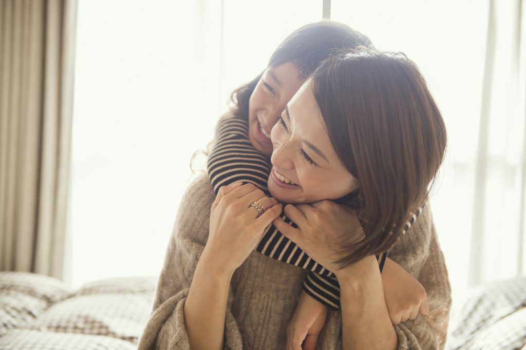 Mother and daughter having fun time in bed room