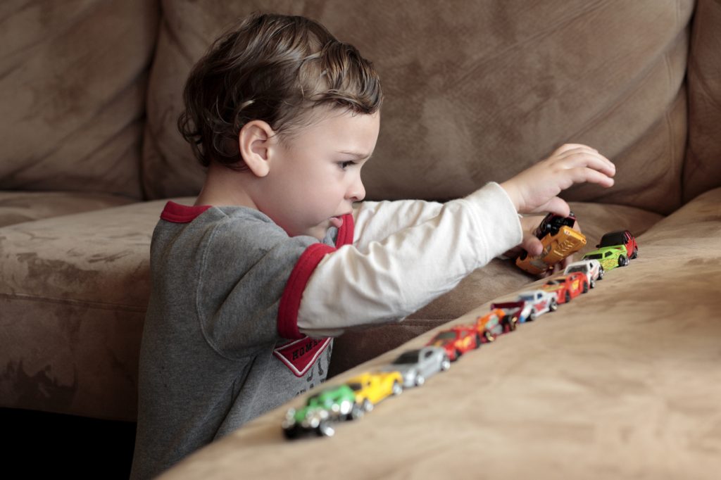 Autistic boy lining up cars to achieve order in his world.