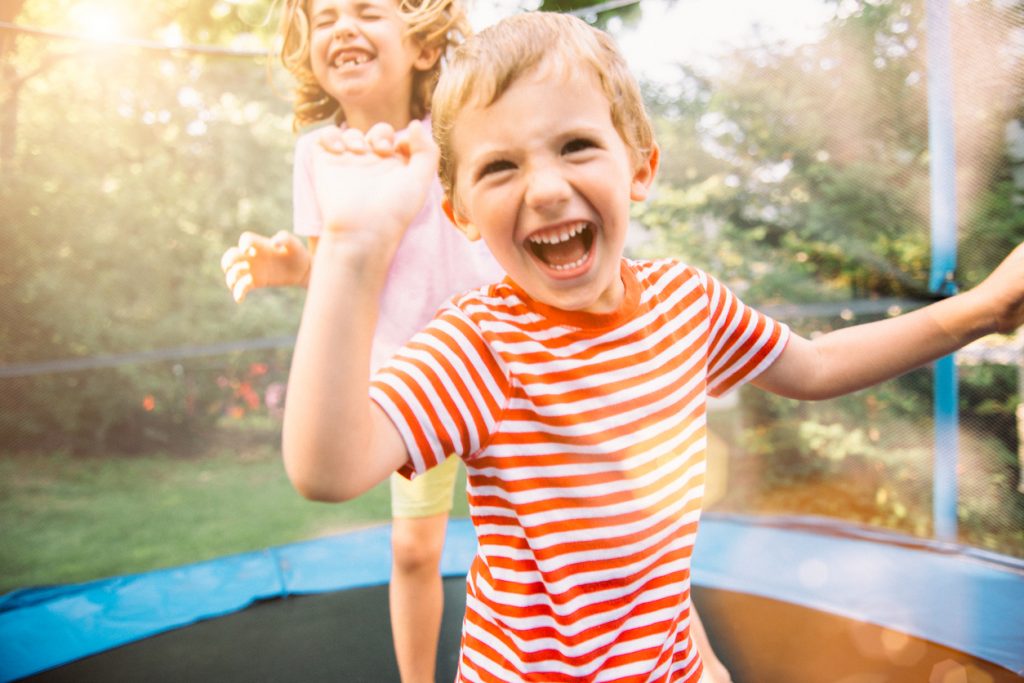 Children having fun on summer vacation jumping on trampoline