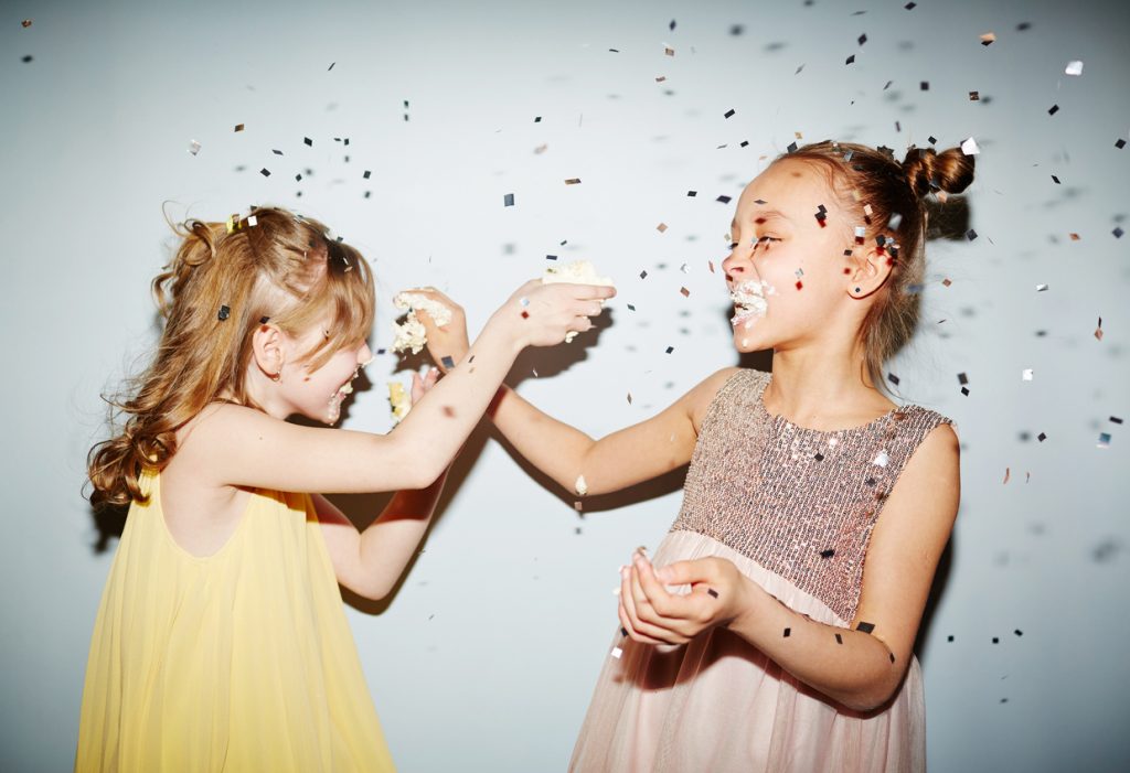 Playing cake Two girls having fun with birthday cake cream at party