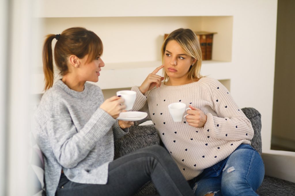 Two young female friends are spending time at home. Young woman is comforting her friend after bad break up.