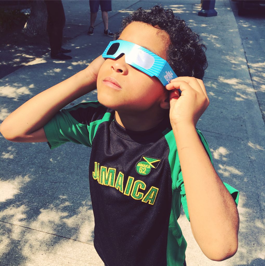 child looking at eclipse through glasses