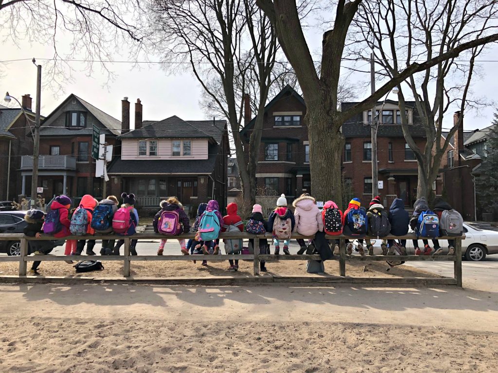 school kids sitting on fence