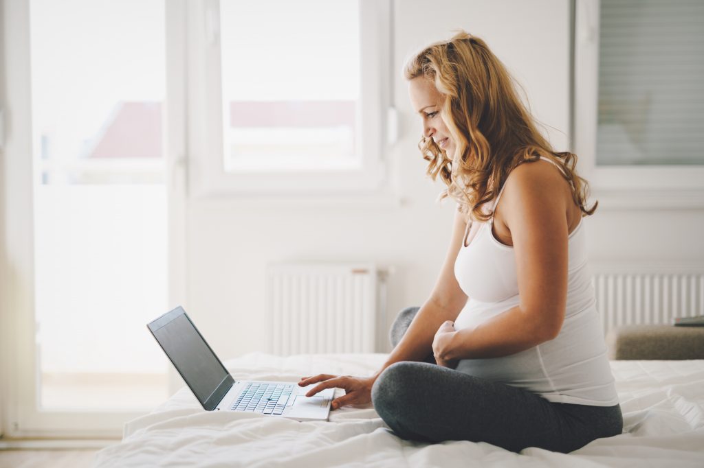 Pregnant expectant and happy  woman using technology from home