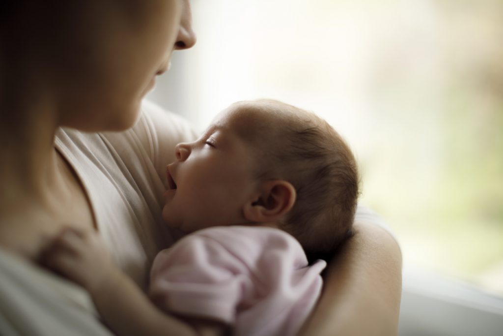 Mother holding her baby girl at home