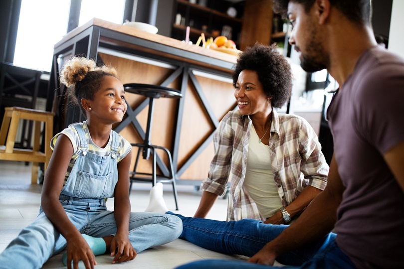 Happy family talking and smiling together at home How to Keep Kids Talking - SavvyMom