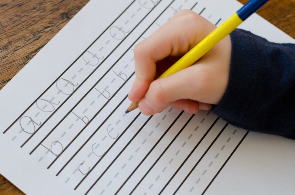 Child practising writing their letters abc