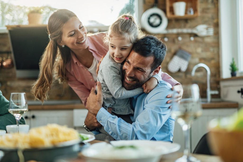 Young loving family embracing in dining room. Father's Day Recipes Dad Will Love - SavvyMom