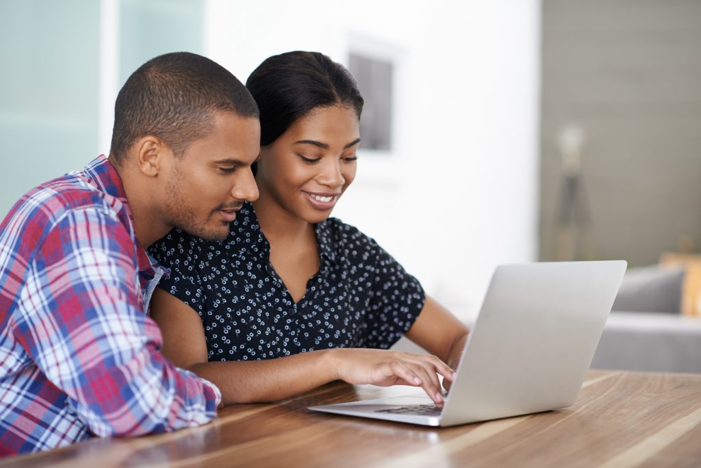 Shot of a young couple sitting at their dining table using a laptop