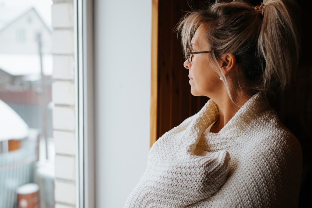 Side view portrait of sad lonely adult caucasian woman wrapped in warm cozy knitted blanket standing by window and looking away, indoors. Depression, meloncholic mood, loneliness, unhappiness concept Quotes for Monday Blues - SavvyMom