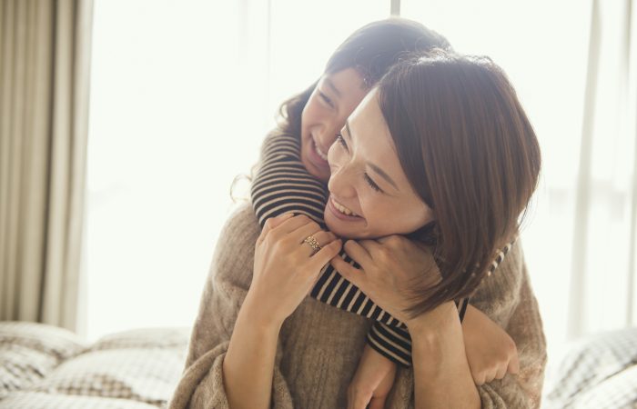 Mother and daughter having fun time in bed room
