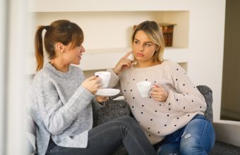 Two young female friends are spending time at home. Young woman is comforting her friend after bad break up.