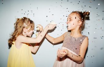 Two girls having fun with birthday cake cream at party