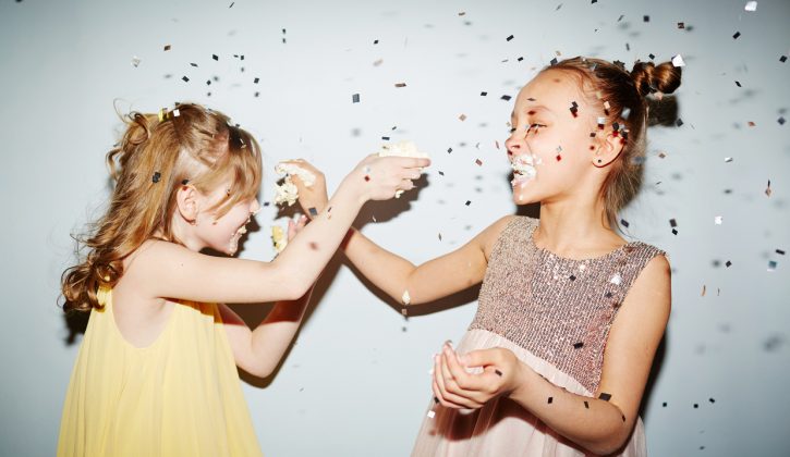 Two girls having fun with birthday cake cream at party