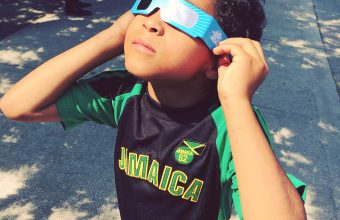 child looking at eclipse through glasses