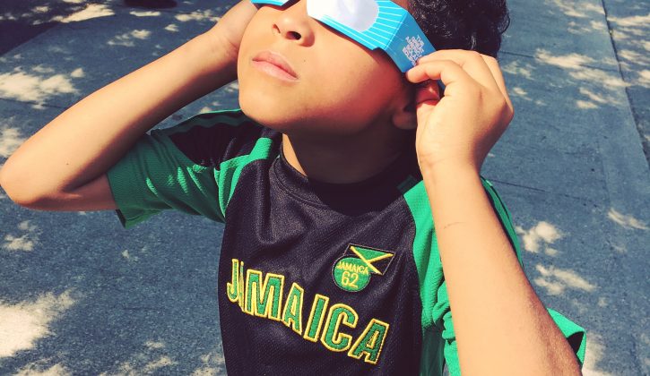 child looking at eclipse through glasses