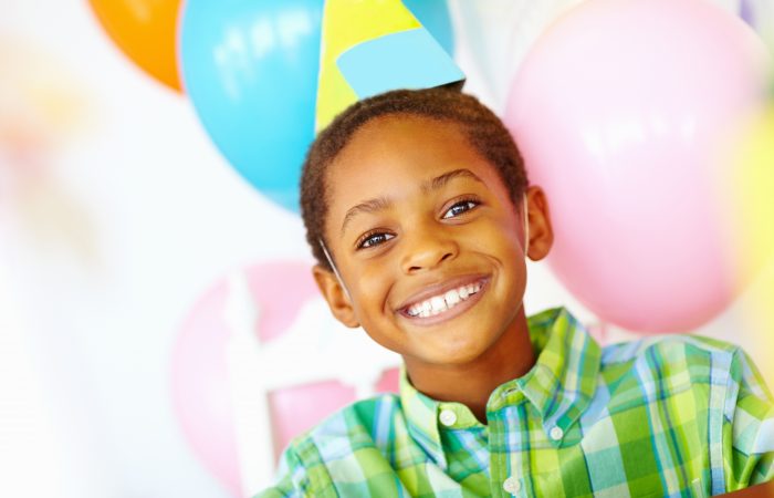 Closeup portrait of an African American birthday boy with balloons in the background