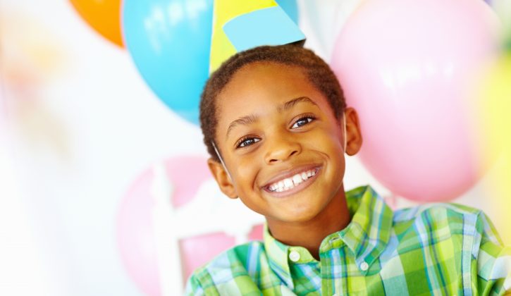 Closeup portrait of an African American birthday boy with balloons in the background
