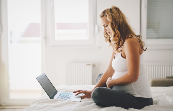 Pregnant expectant and happy  woman using technology from home