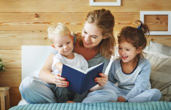 happy family mother reading to   children book in bed