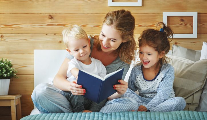 happy family mother reading to   children book in bed