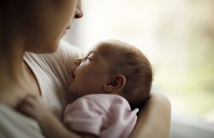 Mother holding her baby girl at home