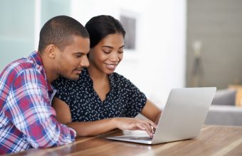 Shot of a young couple sitting at their dining table using a laptop