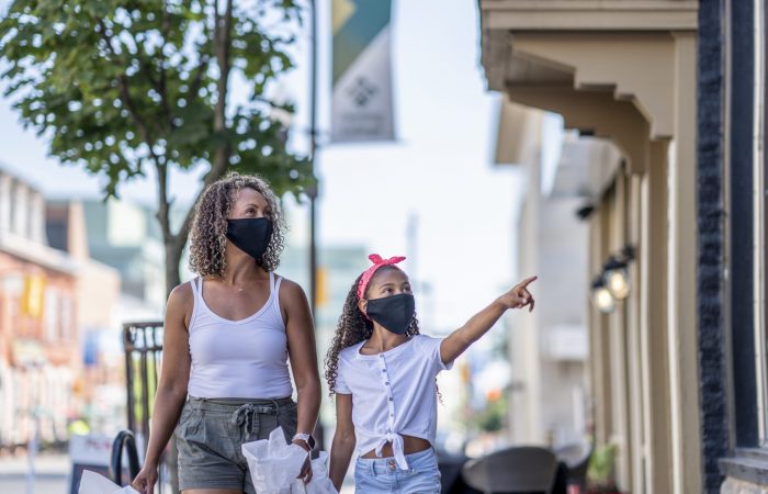 African American mother and daughter shopping downtown while wearing masks
