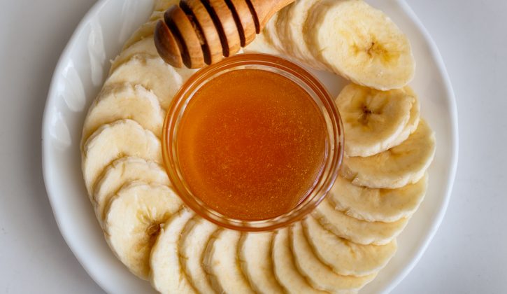 Sliced banana with honey separately on a plate