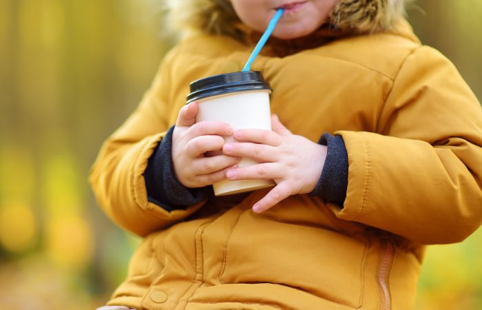 Little child walking in the forest and drinking hot cocoa at cold autumn day. Toddler boy enjoy of fall weather