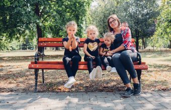 Pregnant mother with daughters in park.