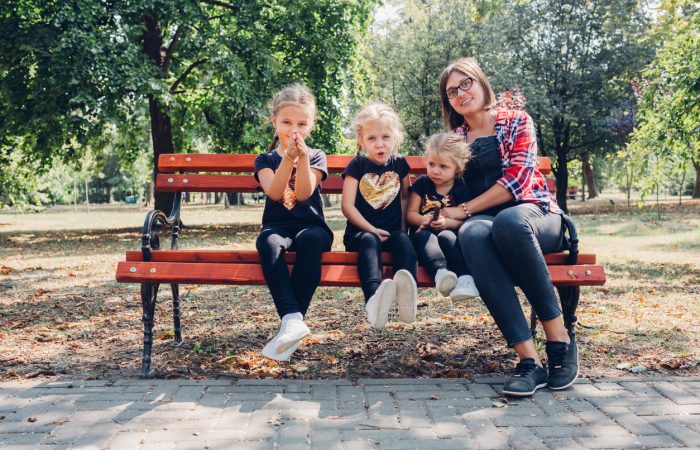 Pregnant mother with daughters in park.