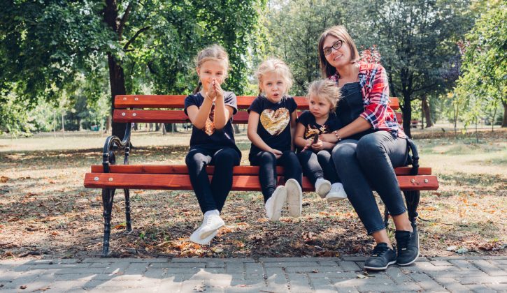 Pregnant mother with daughters in park.