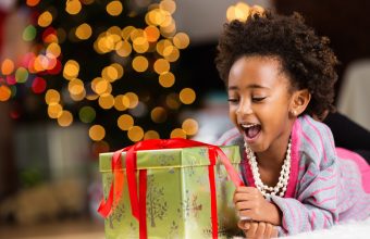 Happy little girl unwrapping Christmas present at home