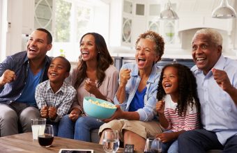 Multi generation black family watching sport on TV at home