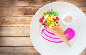 Fruit salad in an ice cream cone on wood background